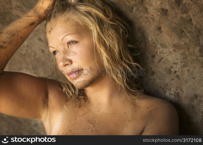 Young topless blond woman with one hand on head.