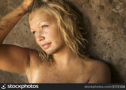 Young topless blond woman with one hand on head.