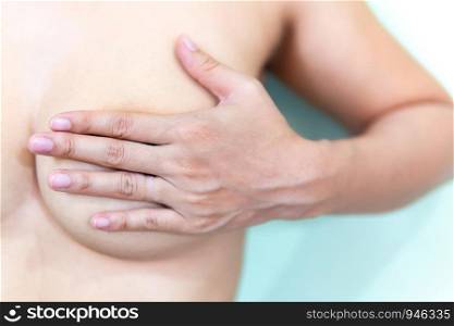 Young topless woman doing breast self-exam (BSE). Checking up breast changes, possible lumps, distortions or swelling. Breast cancer awareness.