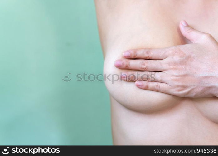 Young topless woman doing breast self-exam (BSE). Checking up breast changes, possible lumps, distortions or swelling. Breast cancer awareness.