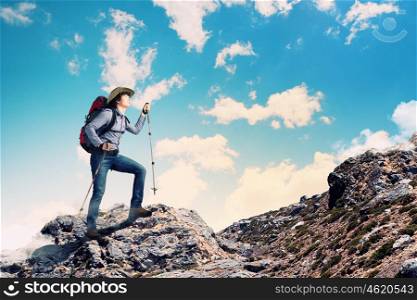 Young tourist atop of mountain. Image of young man mountaineer standing atop of rock