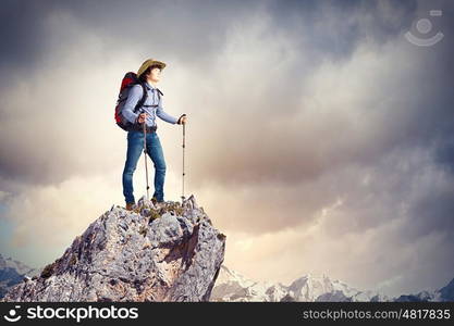 Young tourist atop of mountain. Image of young man mountaineer standing atop of rock