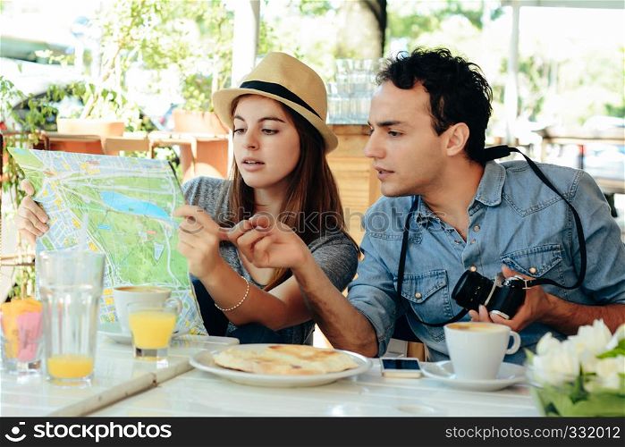 young tourist couple are looking at a map in a restaurant. Travel concept.
