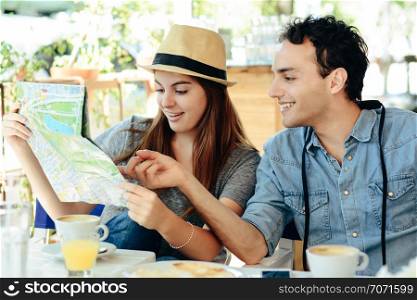 young tourist couple are looking at a map in a restaurant. Travel concept.