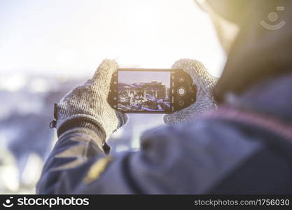 Young tourist man is making a photo of Salzburg with her smartphone, winter time