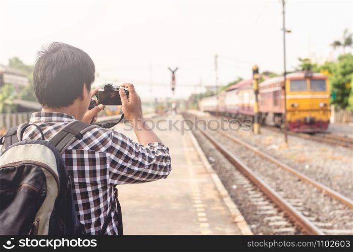 Young tourists are using digital cameras to take pictures of the train running.