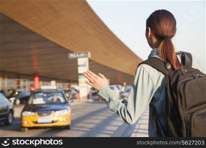 Young traveler hailing a taxi at airport