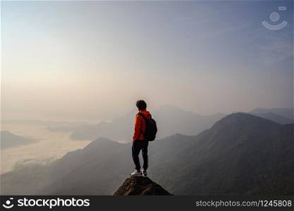 Young traveler standing and looking at beautiful landscape on top of mountain. Young traveler standing and looking at beautiful landscape