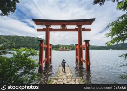 Young traveler takeing photo at red Torii gate of Hakone shrine at lake Ashi, Japan