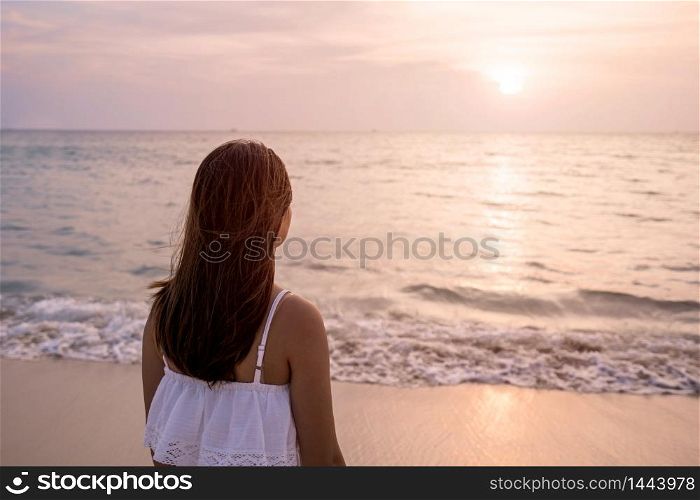 Young traveler woman relaxing on tropical beach at sunset, vacation and summer concept