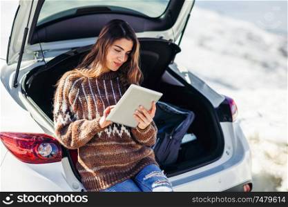 Young traveler woman using digital computer in snowy mountains in winter, in Sierra Nevada, Granada, Spain. Female wearing winter clothes.. Young traveler woman using digital computer in snowy mountains in winter.