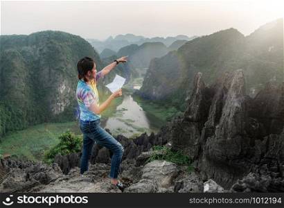 young travelers point to travel through a map in hand. On a scenic hilltop along the way. at Hang Mua, Ninh Binh in Vietnam.