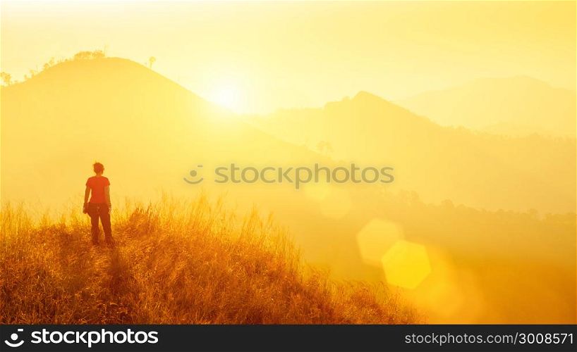 Young traveller standing at mountain at sunrise. Travel, vacation, freedom or success concept.