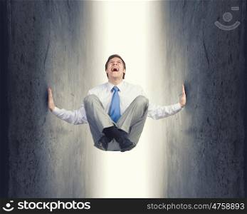 Young troubled businessman trapped between two walls. Under pressure
