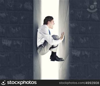 Young troubled businessman trapped between two walls. Under pressure