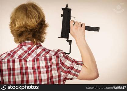 Young unrecognizable man standing backwards holding gun. Private weapon, security service and safety concept.. Man standing backwards holding gun