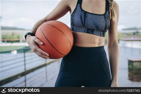 Young unrecognizable sportswoman posing with a basketball outdoors. Sportswoman posing with a basketball
