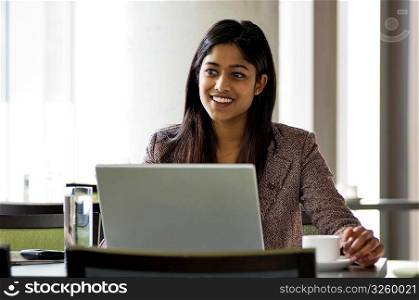 Young urban business woman using a wireless laptop in a hotspot internet cafe.