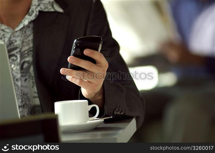 Young urban businessman using Blackberry PDA in cafe.
