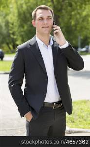 Young urban professional man talking on smartphone. Close up portrait of male business man on smart phone outdoors in suit jacket. Handsome modern guy.