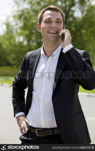 Young urban professional man talking on smartphone. Close up portrait of male business man on smart phone outdoors in suit jacket. Handsome modern guy.