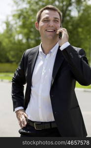 Young urban professional man talking on smartphone. Close up portrait of male business man on smart phone outdoors in suit jacket. Handsome modern guy.