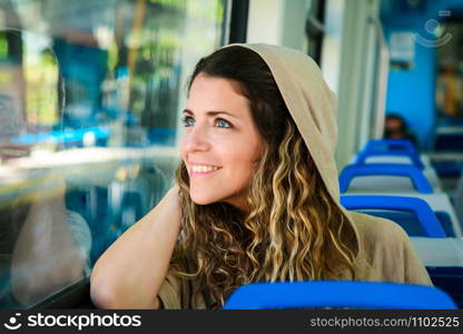 Young urban woman looking through the window in a train. Modern people lifestyle.