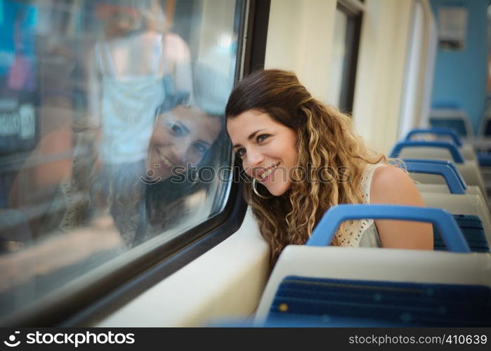 Young urban woman looking through the window in a train. Modern people lifestyle.