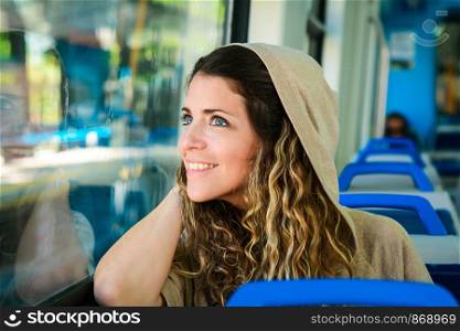 Young urban woman looking through the window in a train. Modern people lifestyle.