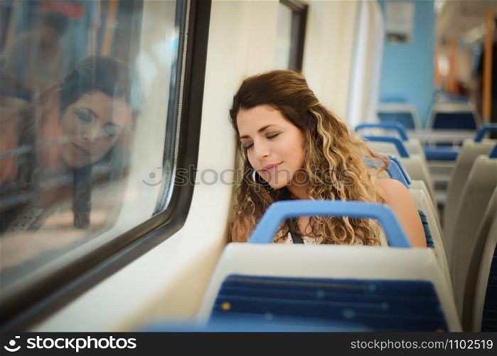 Young urban woman sleeping in a train travel beside the window. Modern people city lifestyle.