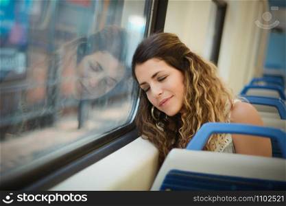 Young urban woman sleeping in a train travel beside the window. Modern people city lifestyle.