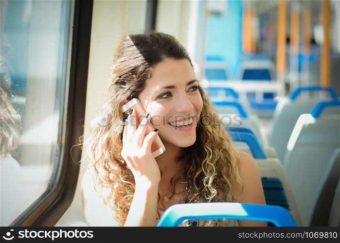 Young urban woman traveling by the train using smartphone. Woman sitting in transport enjoying travel