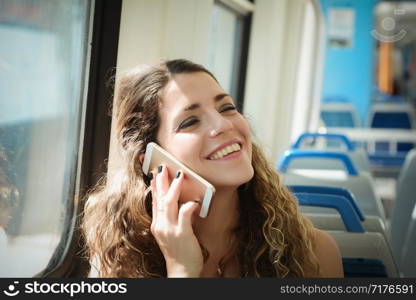 Young urban woman traveling by the train using smartphone. Woman sitting in transport enjoying travel