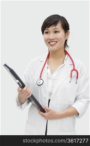 Young veterinarian holding report with stethoscope around neck over gray background