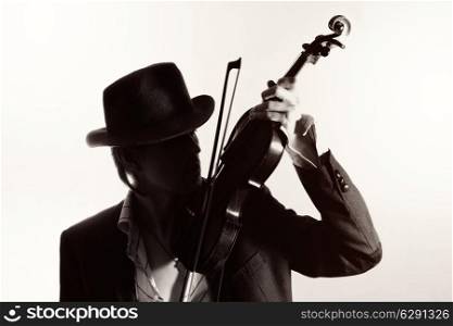 young violinist playing the violin in hat and jacket on a light background