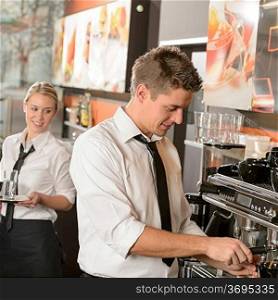 Young waiter and waitress working in bar serving coffee