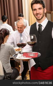 Young waiter hold red wine business lunch at professional restaurant