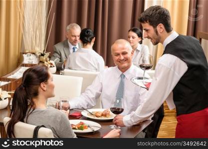 Young waiter serve wine to business people at professional restaurant