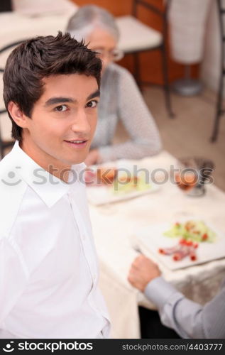 Young waiter serving lunch