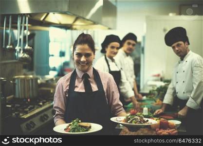 young waitress presenting dishes of tasty meals in commercial kitchen. young waitress showing dishes of tasty meals