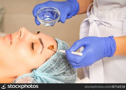 Young white woman getting acid organic retinol peel face skin with the brush in a beauty clinic. Young white woman getting acid organic retinol peel face skin with the brush in a beauty clinic.