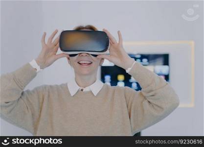 Young white woman in VR headset in office. Interactive design visualisation. Businesswoman working on project in cyberspace and watching video. Excitement from futuristic corporate innovation concept.. Young white woman in VR headset in office. Excitement from futuristic corporate innovation concept.