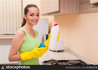 Young wife cleaning kitchen holding bottle