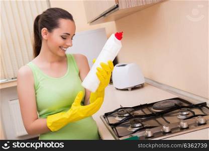 Young wife cleaning kitchen holding bottle
