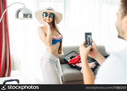 Young wife poses in swimsuit. Fees on journey concept. Preparation for summer vacation. Young wife poses in swimsuit, fees on journey