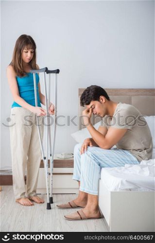 Young wife supporting husband on crutch after injury