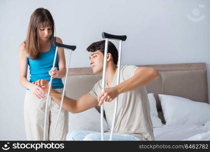 Young wife supporting husband on crutch after injury