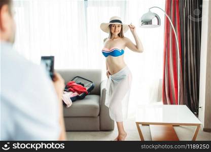Young wife tries on swimsuit before summer vacation. Fees on journey concept. Preparation for summer holidays. Young wife tries on swimsuit before vacation