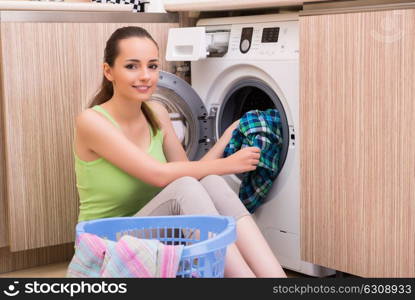 Young wife woman washing clothes near machine