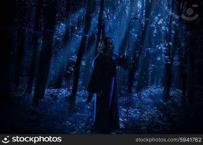 Young witch in night forest